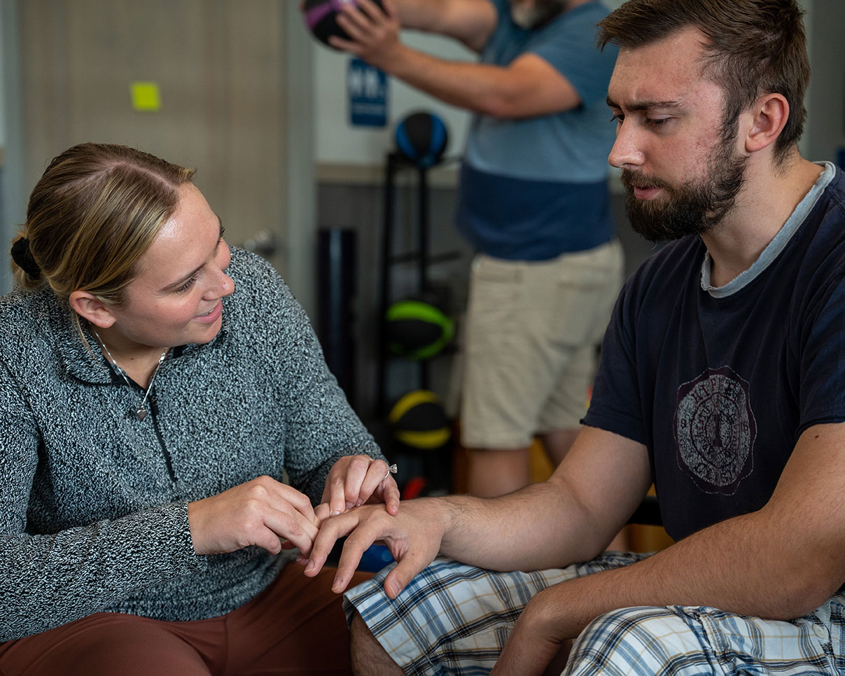 An Occupational Therapy Assistant smiles as she treats her patient.