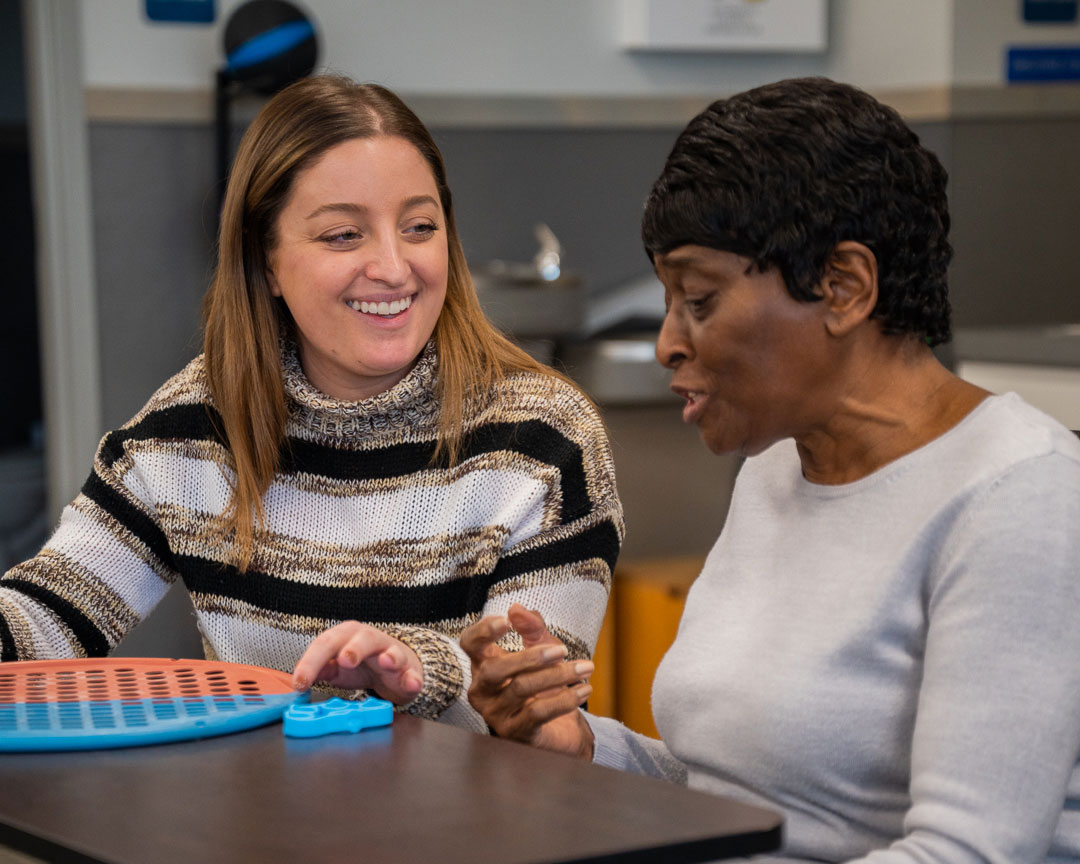 An Occupational Therapist smiles as she treats her patient.