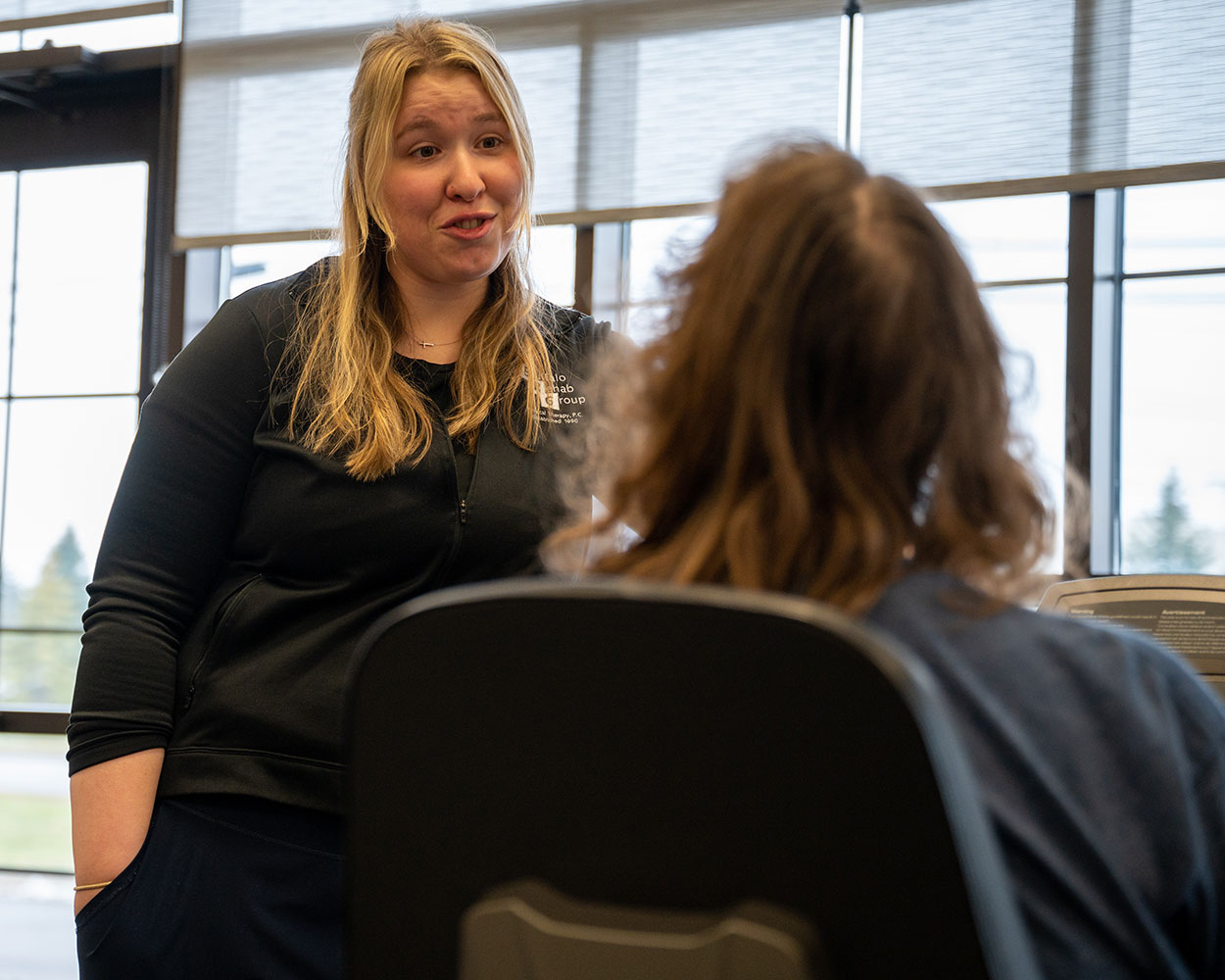A physical therapist assistant happily converses with her patient.