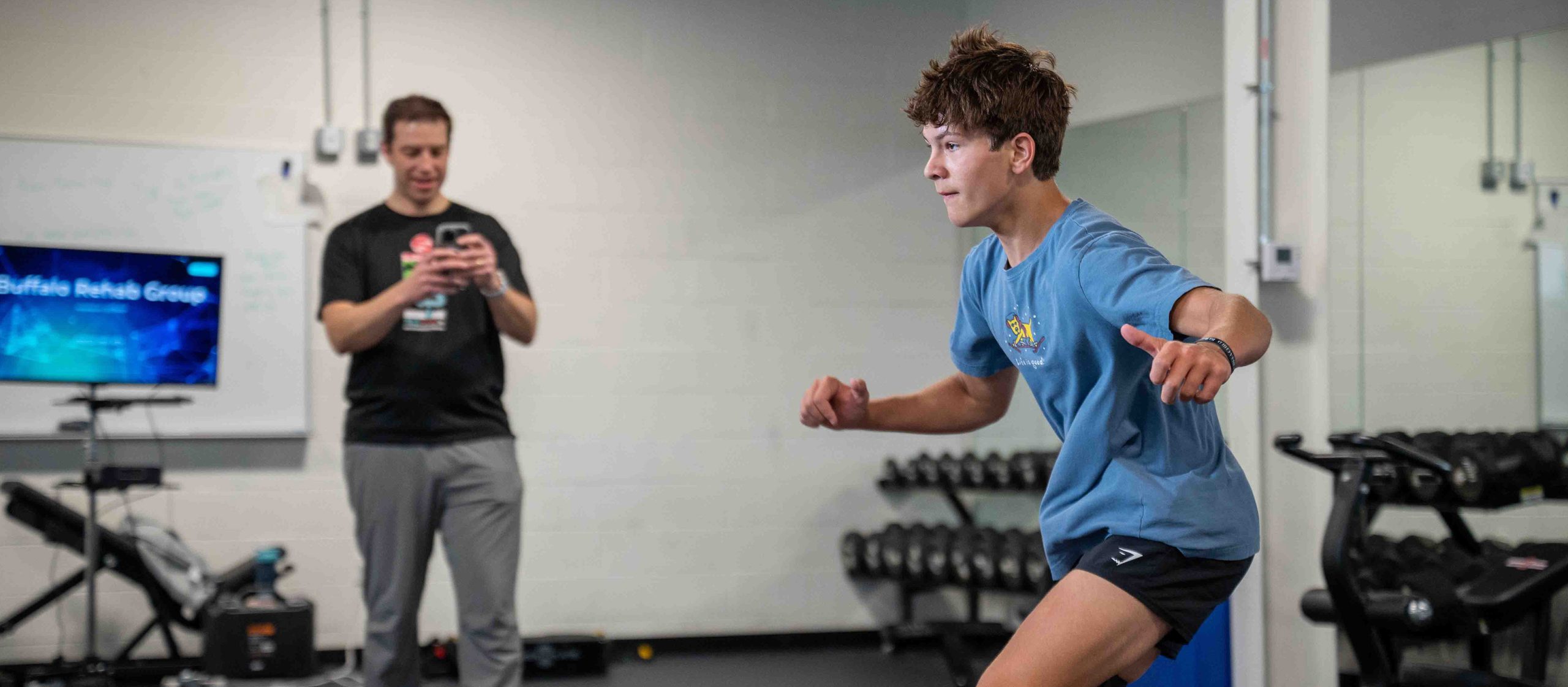 A physical therapist helps her patient balance on a yoga ball.